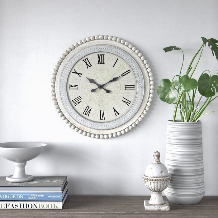 A clock featuring Roman numerals on its face and an elegant beaded trim.