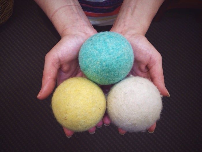 A hand holding three vibrant wool dryer balls
