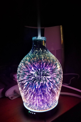 A reviewer's diffuser glowing in the dark, casting cool-toned lights in a firework-like pattern.