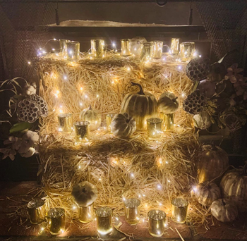 reviewer's gold pumpkins arranged on hay bales surrounded by twinkling lights