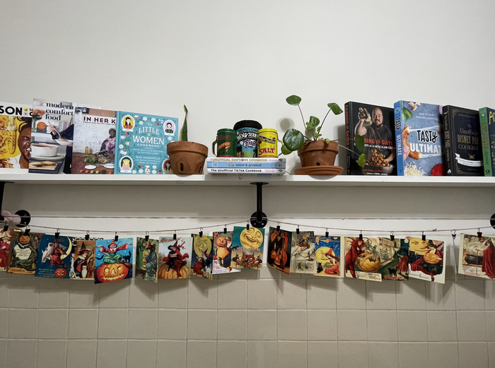 kitchen shelf with cookbooks on top and Halloween cards suspended from twine below