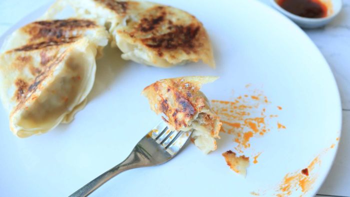 Dumplings are placed on a plate, with one skewered on a fork.