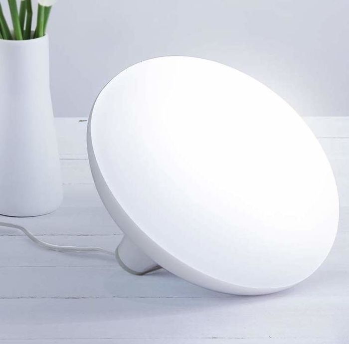 A round, white therapy lamp designed to provide a warm, sun-like glow.
