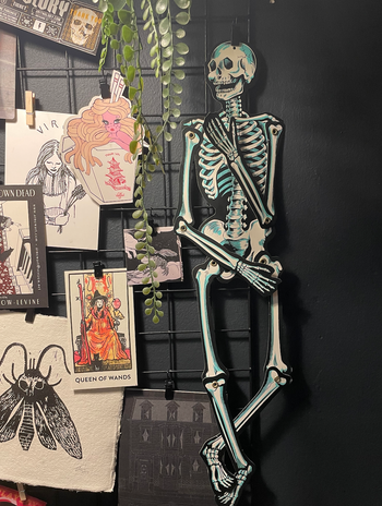 my office wall featuring a skeleton hung on a grid alongside other quirky paper decorations