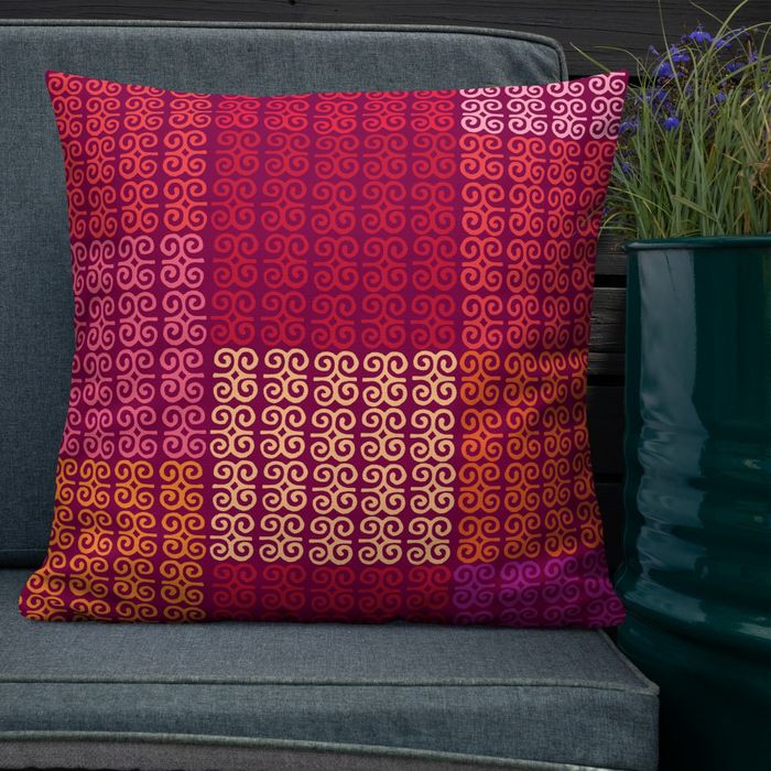 A decorative pillow with a spiraling pattern design, resting on a couch next to a green potted plant.