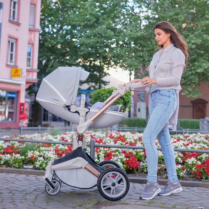 A person walking with a baby in a carriage, the baby resting in a lying position.
