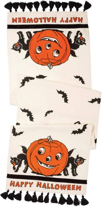 tasseled table runner featuring an illustrated pumpkin, a cat, and the words 'Happy Halloween'