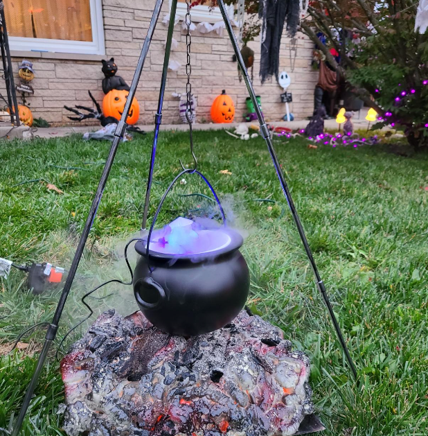 reviewer’s cauldron emitting lights and smoke, used as outdoor decor with a tripod holding it over fake coals