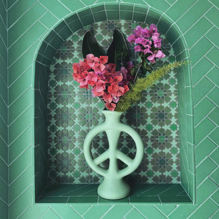 The mint-colored peace sign-shaped vase with flowers inside