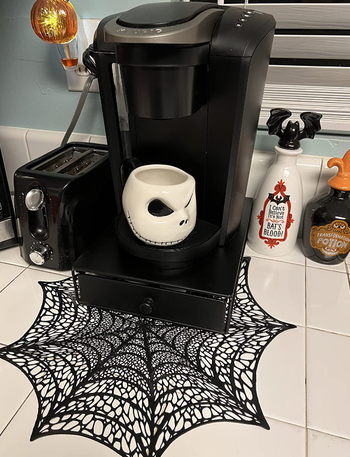 reviewer's coffee maker with the spider web mat placed beneath it