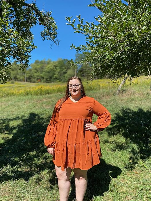 Reviewer modeling the orange dress that falls mid-thigh