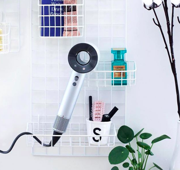 The blow-dryer stored inside a mounted wire rack.