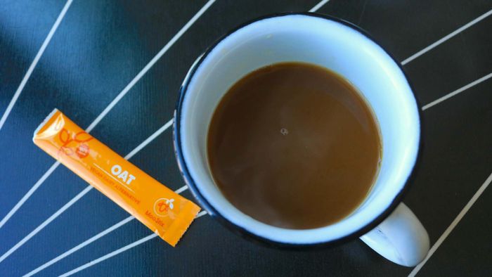 A cup of coffee accompanied by a Moo Stix packet, now empty.