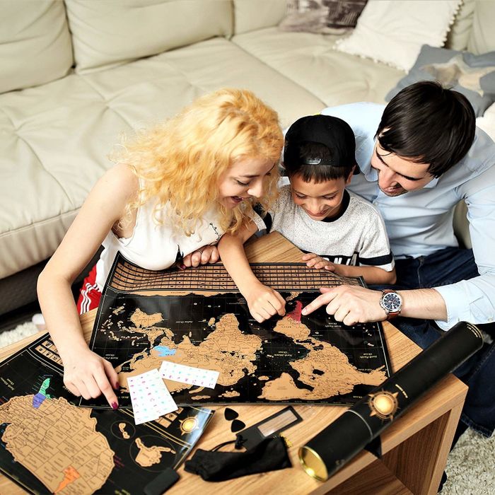 A family scratching off places on the gold map against a black background