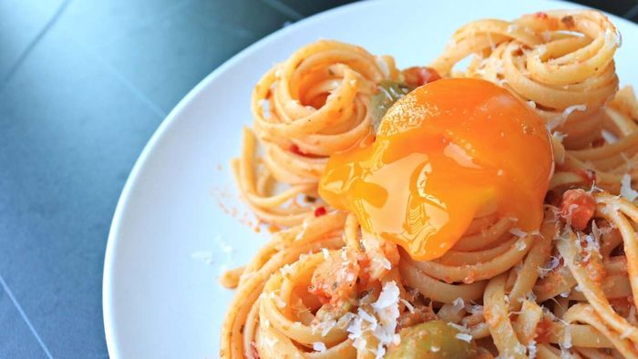 A broken egg yolk crowned atop a plate of pasta is a simple yet luxurious touch.