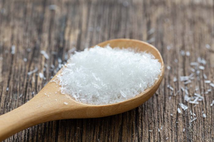 A close-up view of a spoonful of MSG flakes