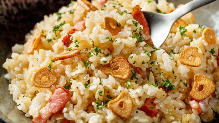A bowl of rice adorned with crunchy garlic chips and savory bacon.