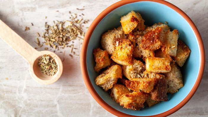 A bowl filled with croutons resting on a table.
