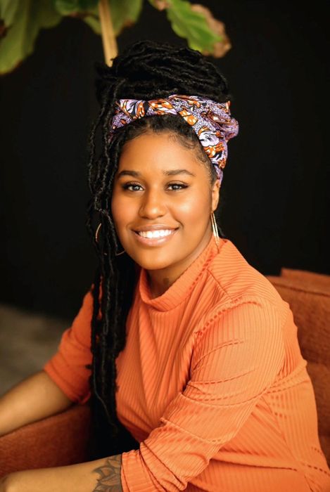 a model wearing the purple and orange headwrap to support their locs