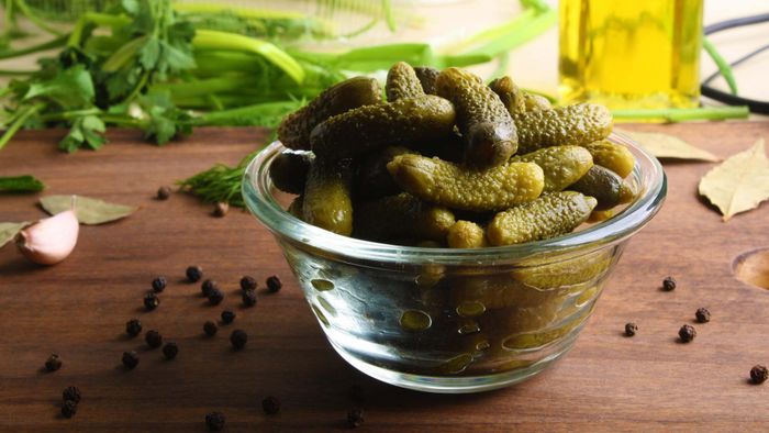 A bowl of gherkins resting on a table.