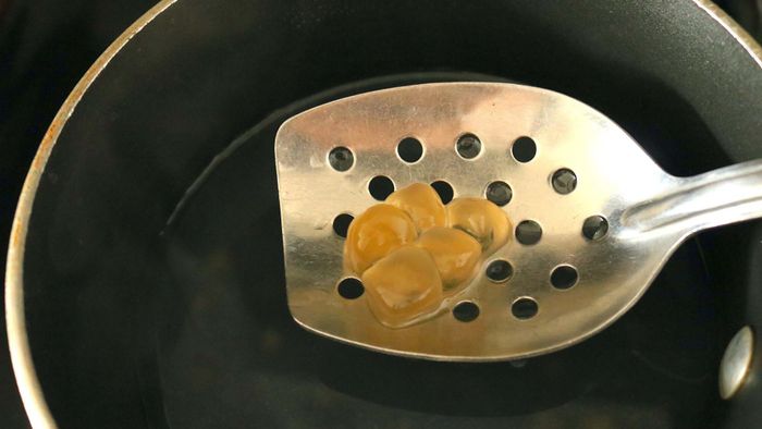Tapioca pearls being lifted out of a pot with a slotted spoon.
