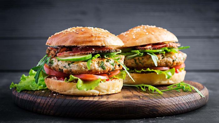 Two turkey burgers rest on a cutting board.