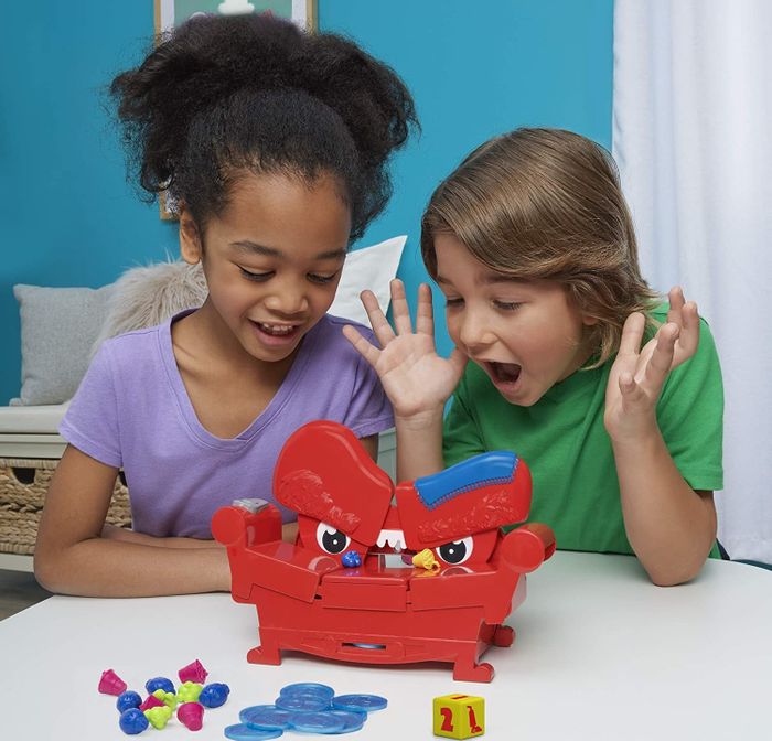Two children having fun playing with a red plastic couch game.