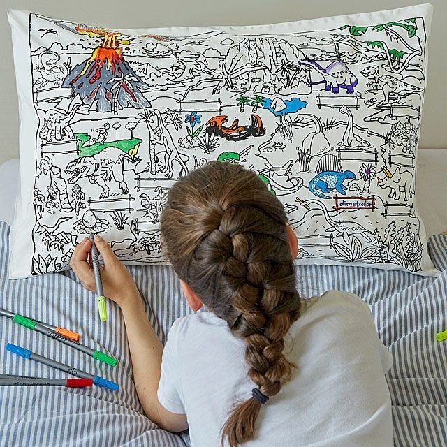 A child model coloring on a pillowcase featuring a playful dinosaur scene