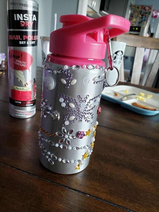 A reviewer's photo showcasing a water bottle decorated with sparkling rhinestone glitter gem stickers.