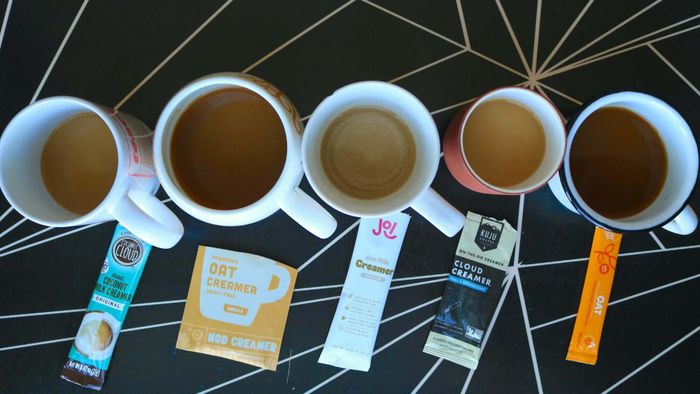 Coffee cups with various non-dairy creamers placed on a table.