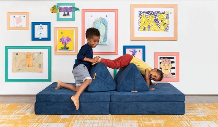 Two models enjoying playtime on the blue Nugget couch, showcasing its versatility and fun.