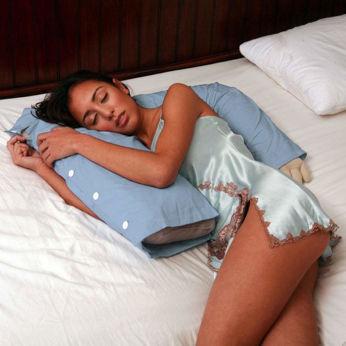 A model cuddled by the pillow shaped like a torso with an arm.