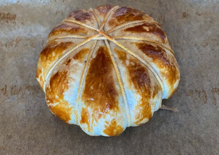 A finished baked brie, still wrapped in puff pastry and string.