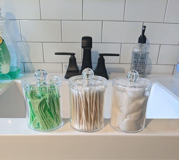 Three glass jars filled with flossers, Q-tips, and cotton balls.