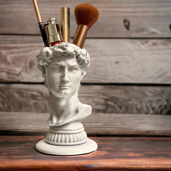 A bust-shaped organizer holding makeup brushes, placed on a wooden surface, featured in a shopping guide on innovative storage ideas.