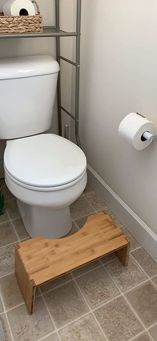 a reviewer photo of the light wood stool placed in front of a toilet