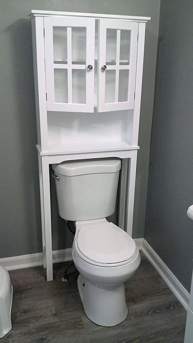 A reviewer photo showing the white cabinet placed above a toilet.
