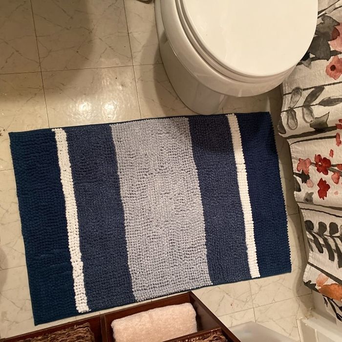 A photo of the blue striped bath mat placed in front of a toilet.