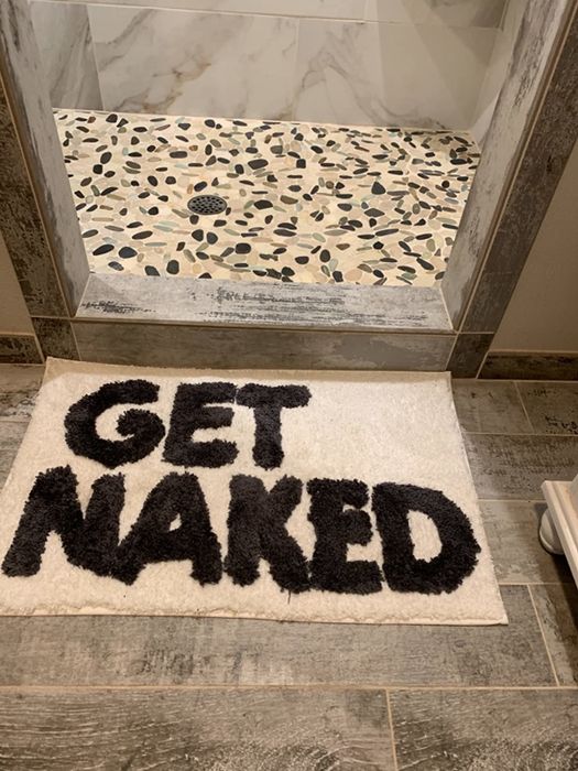 A reviewer’s image showing a black and white bath mat with the phrase 