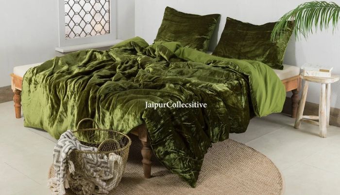 A green crushed velvet duvet cover with matching pillowcases, set against a light wooden bed frame with crisp white sheets.