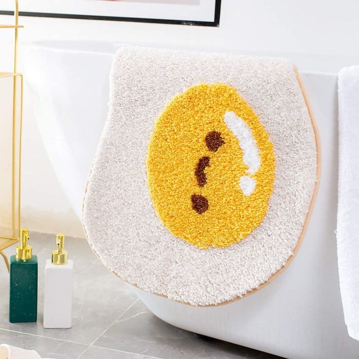 A lifestyle image of the egg-shaped bath mat draped over the side of a bathtub.