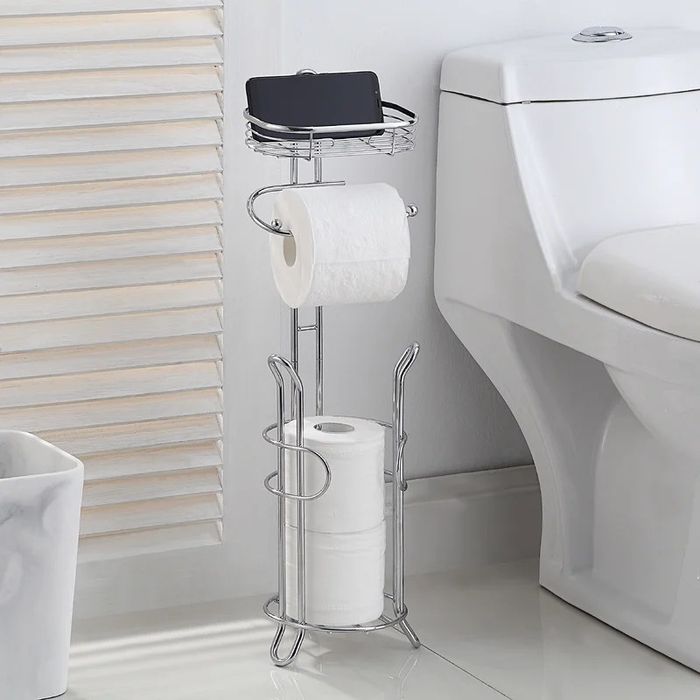 A chrome toilet paper holder with space for spare rolls and a convenient tray on top for extra storage
