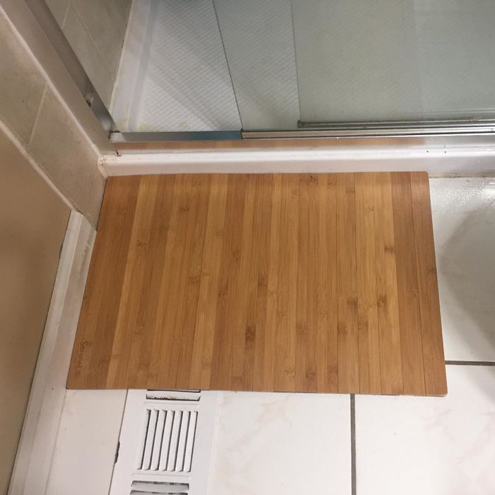 A reviewer image of the bamboo mat placed in front of a shower.