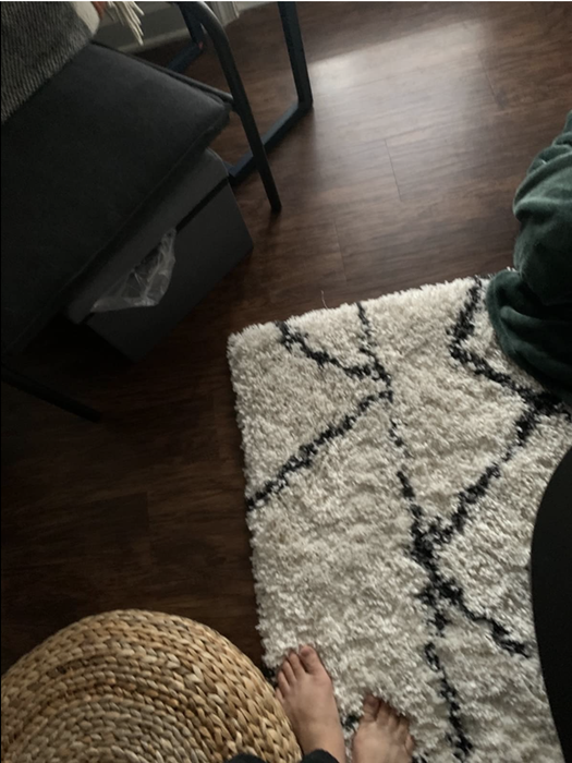 A reviewer photo of a rug on the floor, demonstrating that the rug grippers are virtually undetectable underneath.