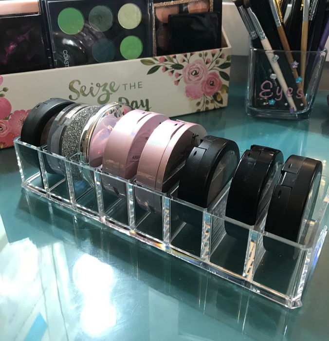 A vanity adorned with makeup organizers holding eyeshadows, palettes, and brushes; featured as part of a beauty shopping article.