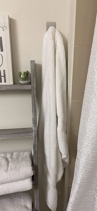 A reviewer's photo showing a silver hook holding a white towel in a beautifully decorated bathroom.