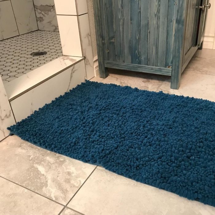Reviewer photo featuring a blue bath mat placed in front of a shower