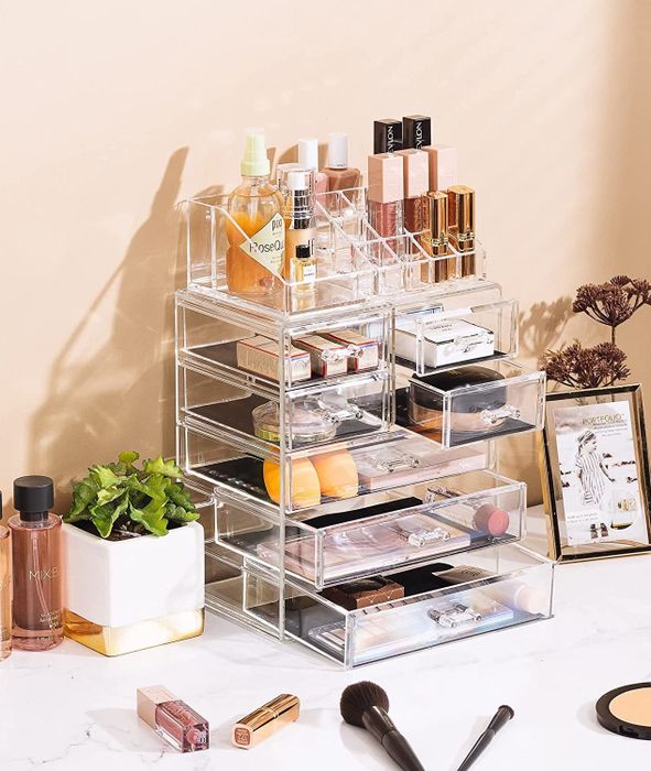 The clear makeup organizer with drawers open, each compartment neatly filled with various items.