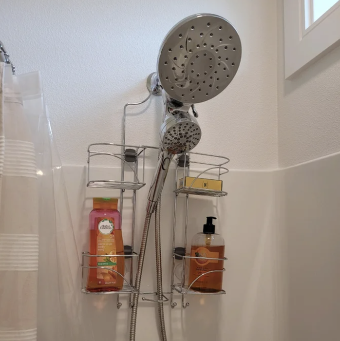 The shower caddy positioned over a shower head, filled with bottles of shampoo and conditioner