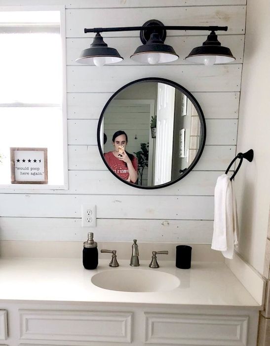A photo showing the sconce placed above a mirror in a bathroom.